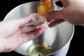 Pouring yolk from shell to shell above metal bowl Royalty Free Stock Photo
